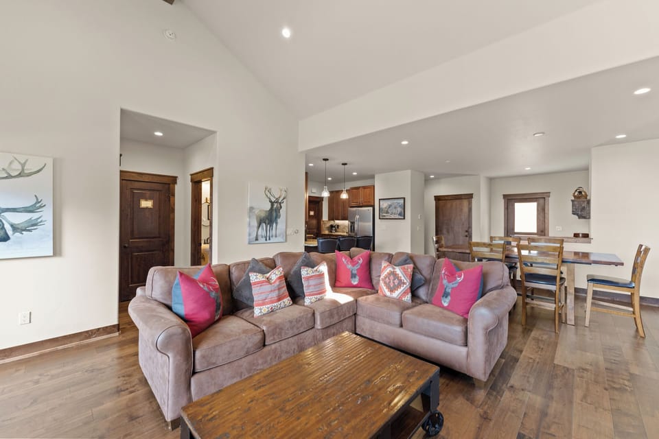 Relax in your spacious open-concept living area with plush sectional seating, rustic wood accents, and modern mountain charm.