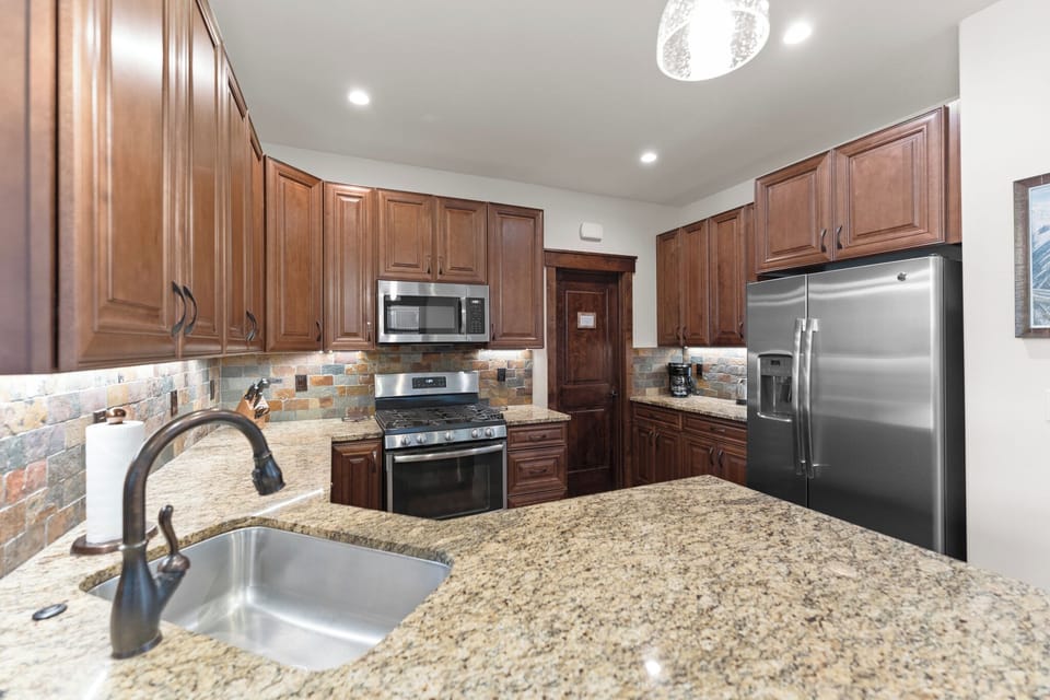 Your spacious kitchen features granite counters, rich wood cabinetry, and stainless steel appliances—everything you need for memorable meals together.