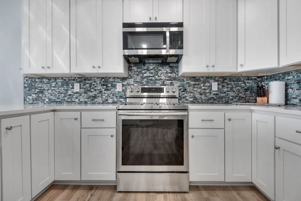 White cabinets, quartz counters, and mosaic backsplash bring in the beach vibe.