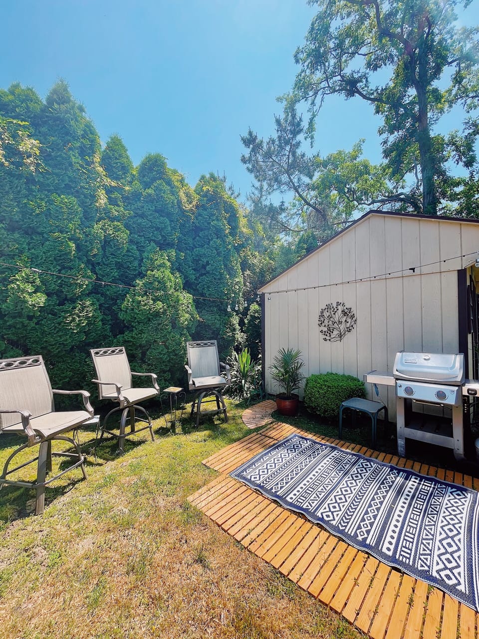 grilling area of large backyard with cedar decking and bar stools 