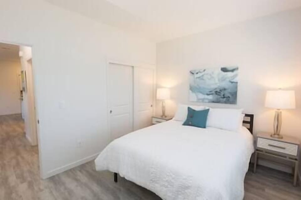 Bedroom 2 features a queen bed, warm lighting, two nightstands, and serene view of the olive orchard