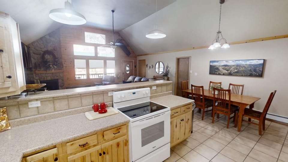 Your well-equipped kitchen invites you to prepare delicious meals while gathering with loved ones at the spacious dining table. Natural light pours in as the cozy fireplace and vaulted ceilings create a warm, open atmosphere.