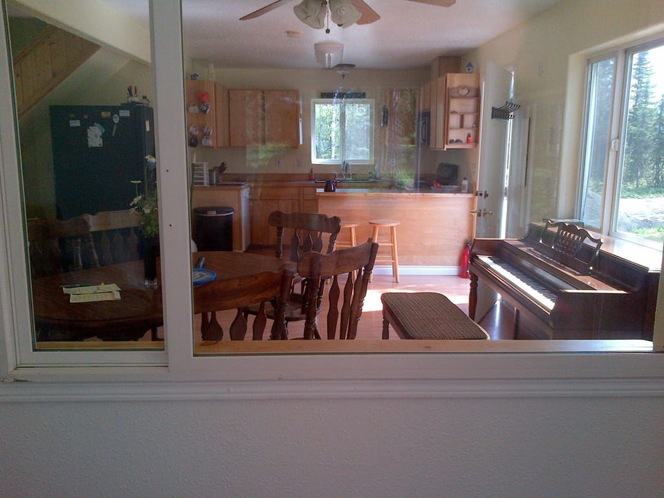 dining and kitchen, frig on left, stair far left, piano
