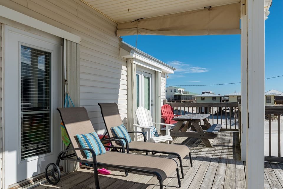 Your private deck awaits with comfortable loungers and dining space, perfect for morning coffee or sunset cocktails overlooking the coastal neighborhood.