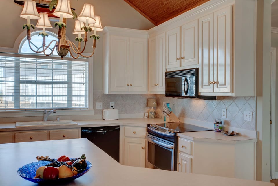 Your fully equipped kitchen awaits with warm chandelier light, sleek appliances, and charming details for memorable meal prep.
