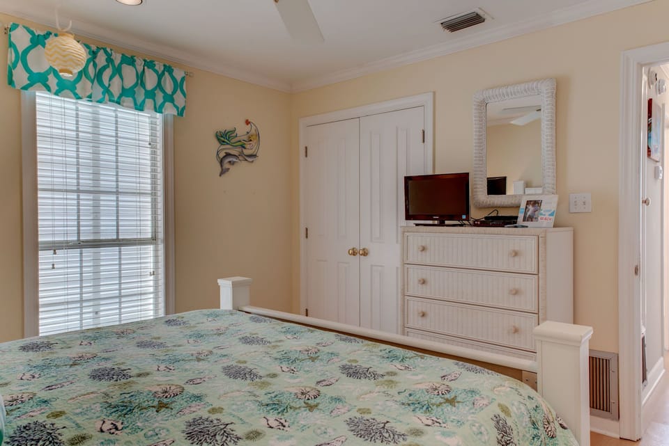 Unwind in your coastal-themed bedroom with soft linens, entertainment center, and cheerful tropical touches that make every morning feel like vacation.
