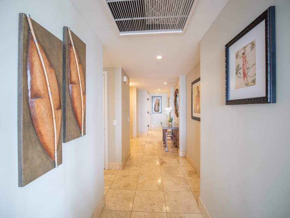 Stylish hallway featuring tropical artwork and warm lighting, leading to spacious bedrooms.