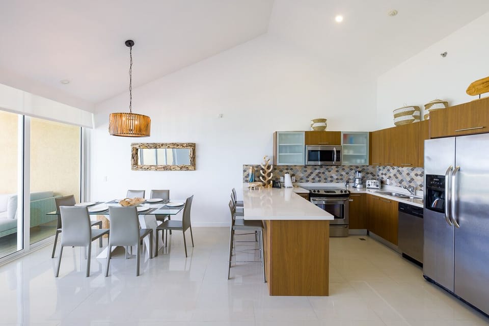 Prepare your favorite meals in this modern kitchen with stainless steel appliances and share them at the bright dining table under beautiful pendant lighting.