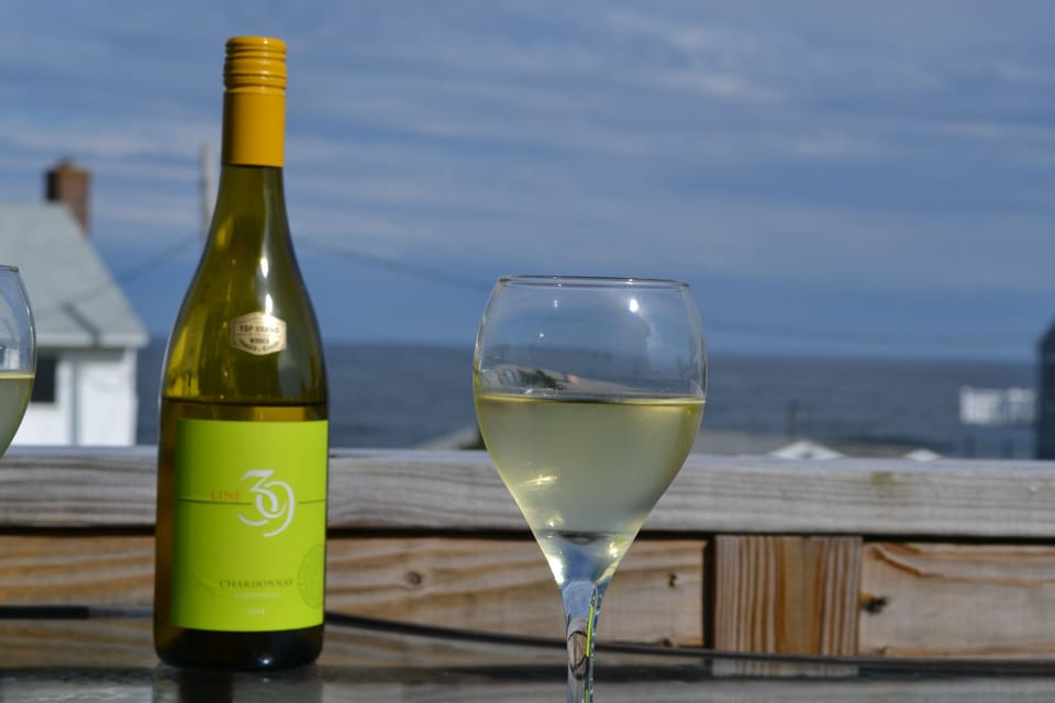 Care free w/ a cool  drink on the deck after a day at the beach as the sun sets