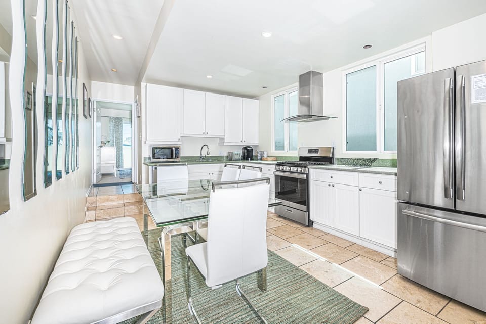 Dining table with bench and chair seating sits within the kitchen on one side and the central staircase on the other. Located on middle (main level).
                