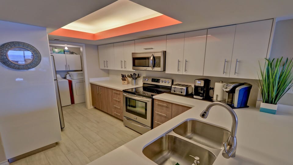 Sleek,  fully stocked modern kitchen with polished quartz countertops.