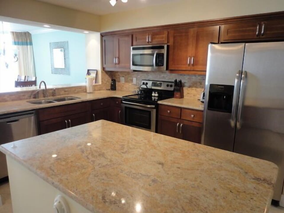 View of kitchen across island from entry foyer with stainless appliances 