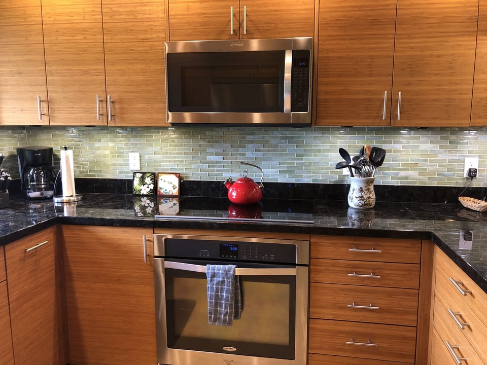 Kitchen with custom bamboo cabinetry, microwave, glass top stove, full size oven