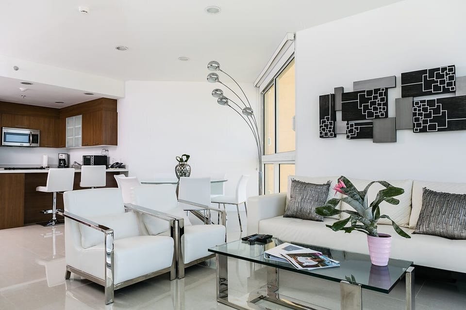 Your sleek, modern space blends style and comfort. Gleaming tile floors, statement art, and fresh greenery invite you to unwind in this bright, airy living area with a fully equipped kitchen nearby.