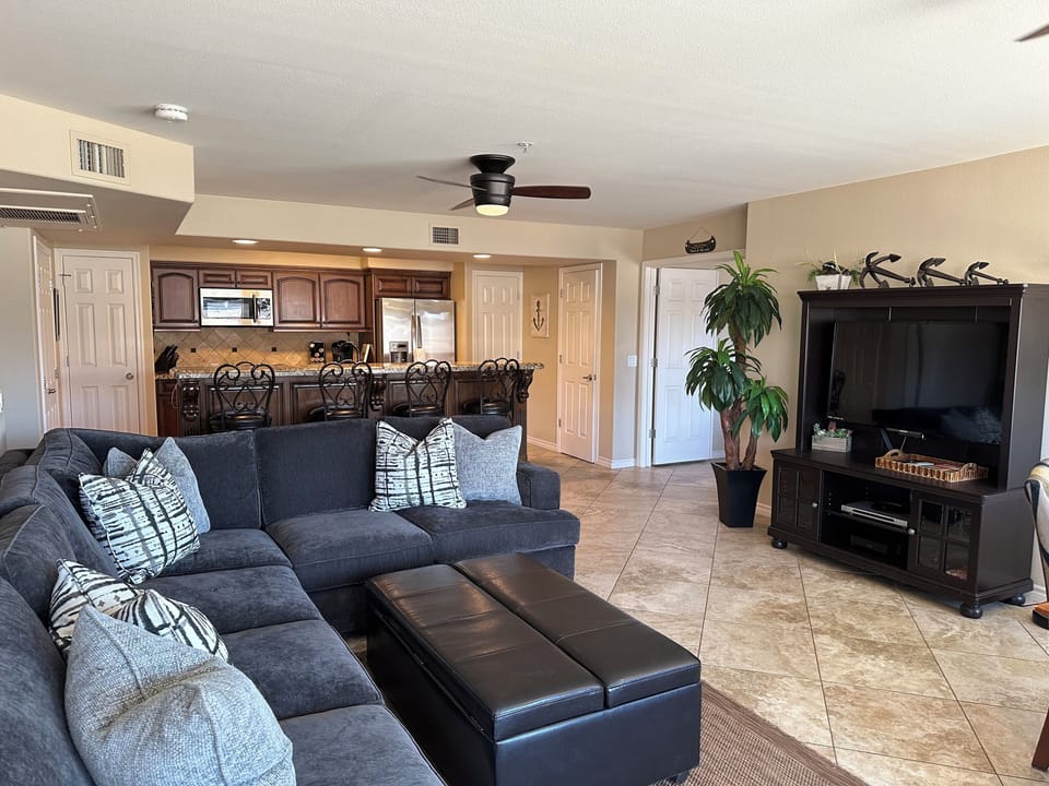 As you walk in, see open living area, tv, bar,  and kitchen.