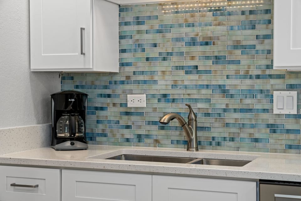 Kitchen with beautiful new quartz countertops and blue/green glass tile back