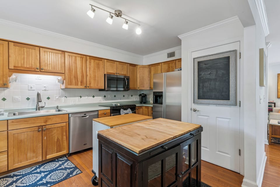 Your fully equipped kitchen awaits with warm wood cabinetry, modern appliances, and a handy island for meal prep and casual dining.