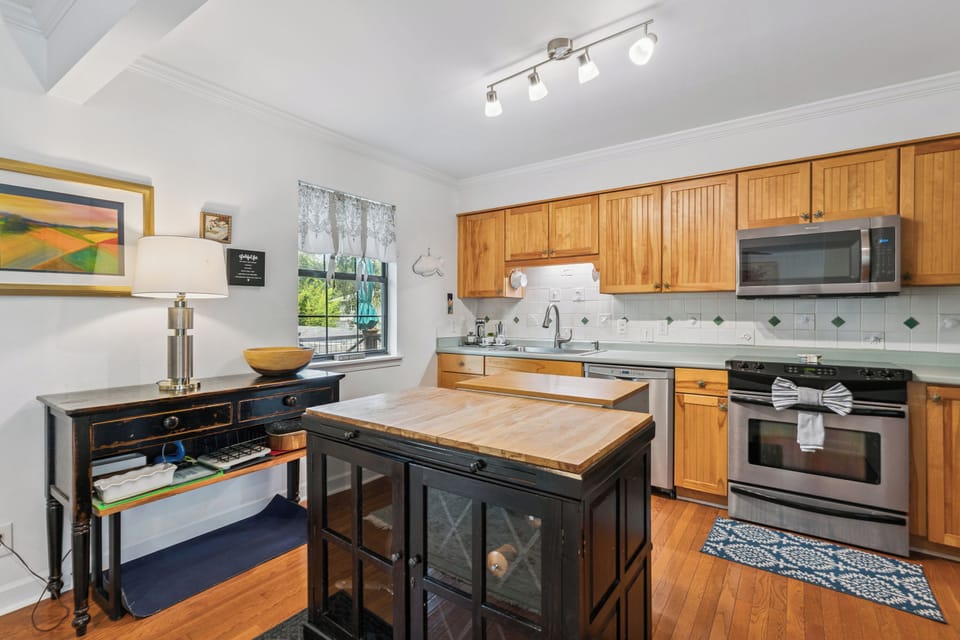 Your fully equipped kitchen invites you to prepare meals with ease, featuring warm wood cabinetry, modern appliances, and a charming butcher-block island at the heart of the space.