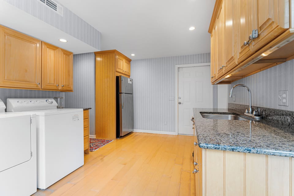 Laundry area just off the kitchen with washer, dryer, second fridge/freezer and access to pool and backyard
