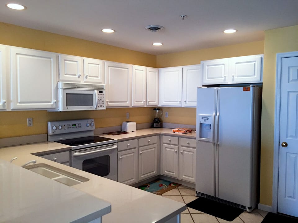 Side-by-side refrig with ice maker.  Utensils are there to cook a gourmet meal!