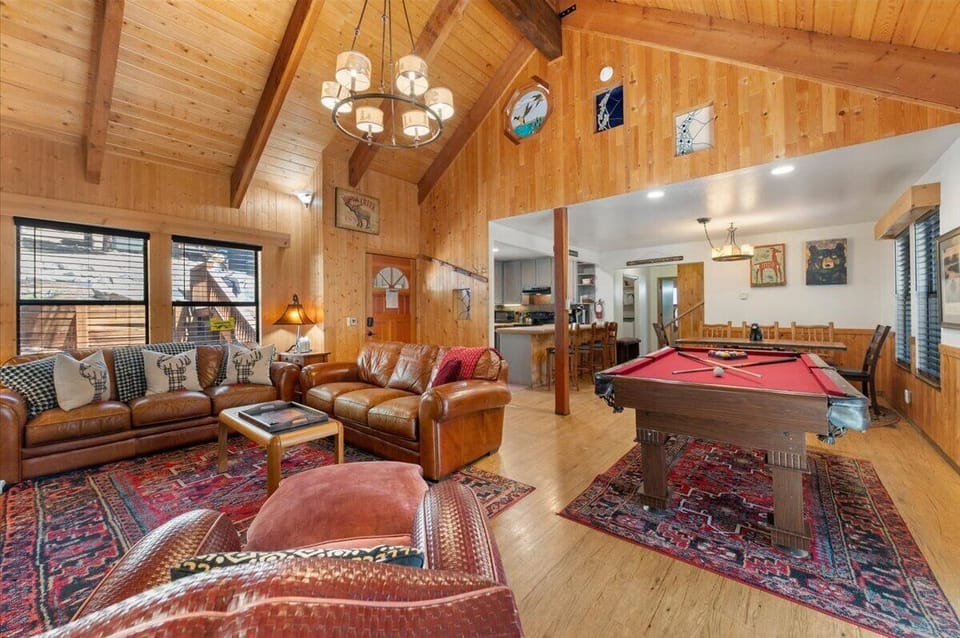 Large open great room with wood burning fireplace, slider to back deck, pool table, and TV.