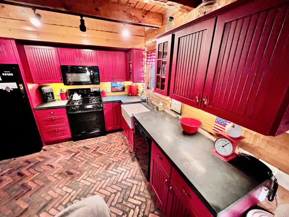 Kitchen w fridge, microwave, dishwasher, concrete counters, & stocked cabinets.