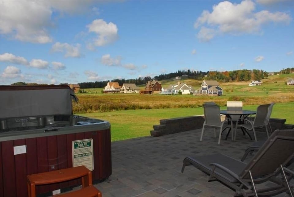 Patio with hot tub next to the swimming pool overlooking golf course
