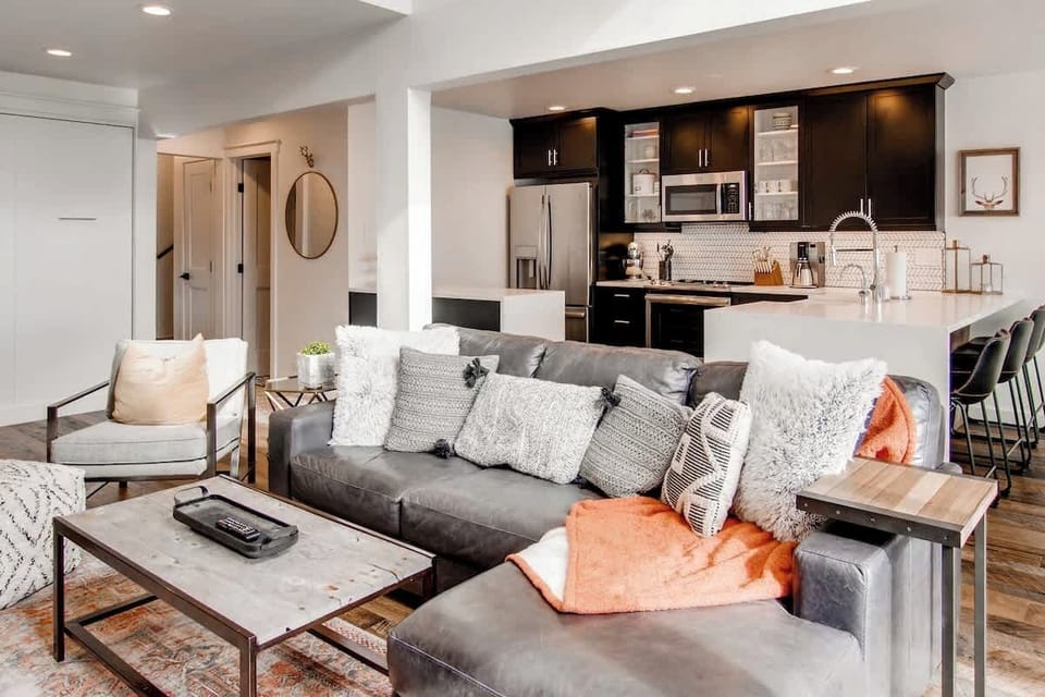 Updated kitchen with quartz waterfall counters and bar seating, and leather sectional sofa.