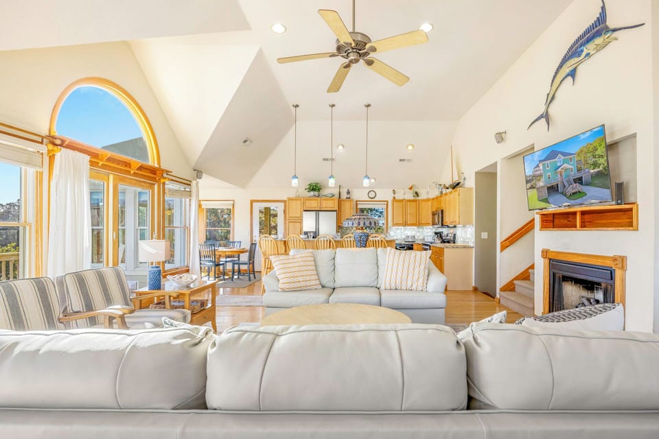 Unwind in this airy coastal living space where vaulted ceilings and panoramic windows create your perfect retreat.