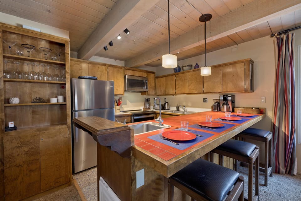 Fully equipped kitchen now with stainless appliances, spacious breakfast bar and warm wood accents