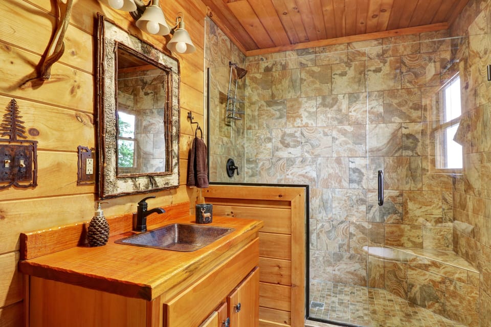 Loft bedroom has adjoining bathroom with glass door entry shower.