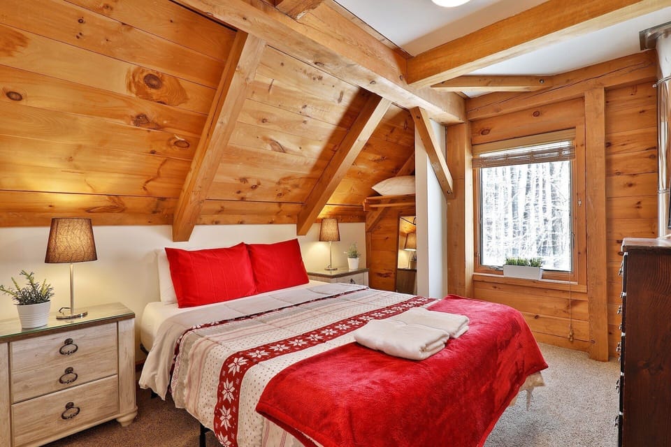 Angled wood ceilings and a window give this bedroom its classic cabin character.
