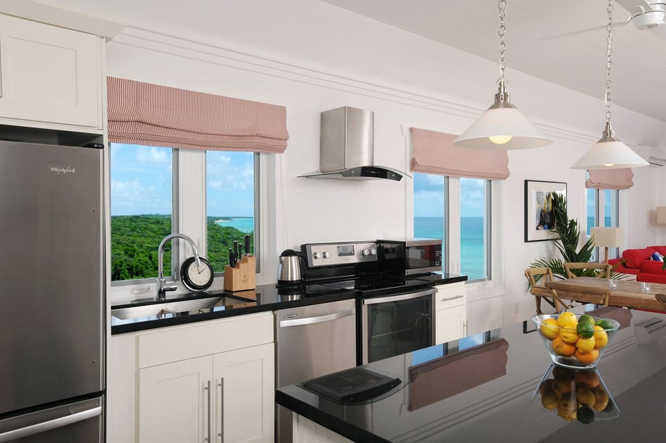 Modern kitchen in black granite and stainless steel, with views of both oceans.