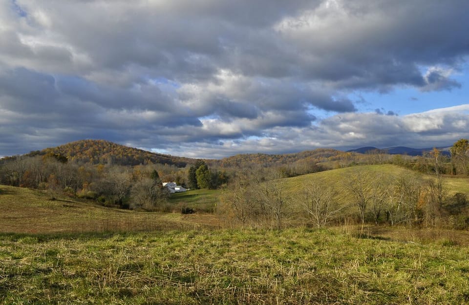 Photo from the back pasture showing the farm and surrounding rolling hills.