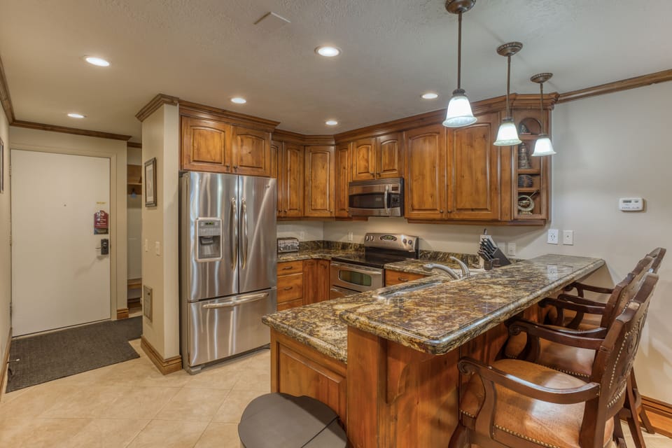 View of kitchen, entrance, and bar seating area.