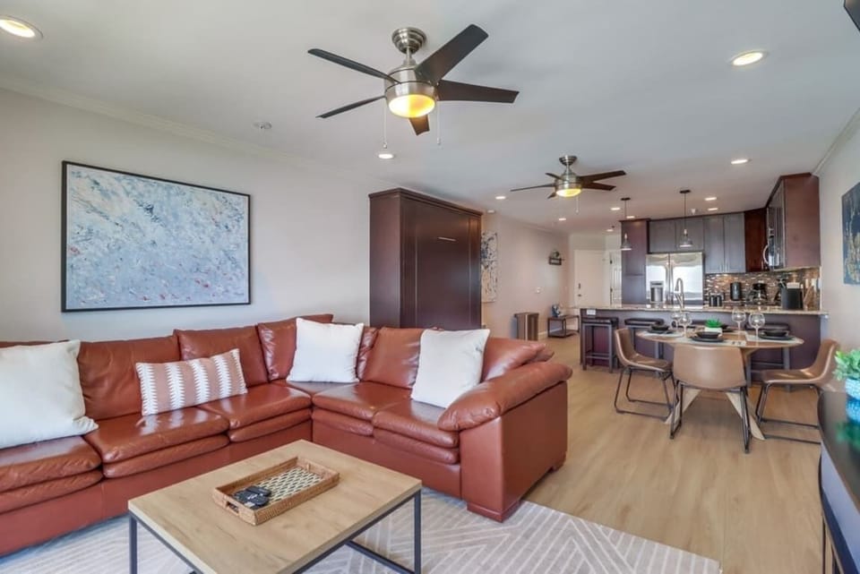 Timeless decor featuring leather couch, ceiling fan, Murphy bed, dining table and open-style fully equipped kitchen