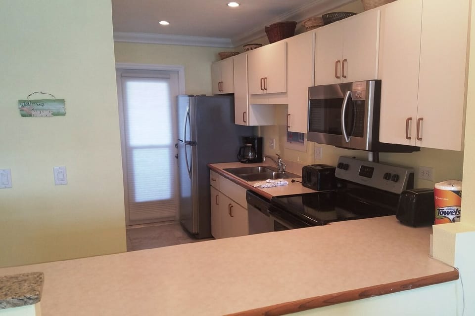 Fully equipped kitchen opens to living/dining area and window/door