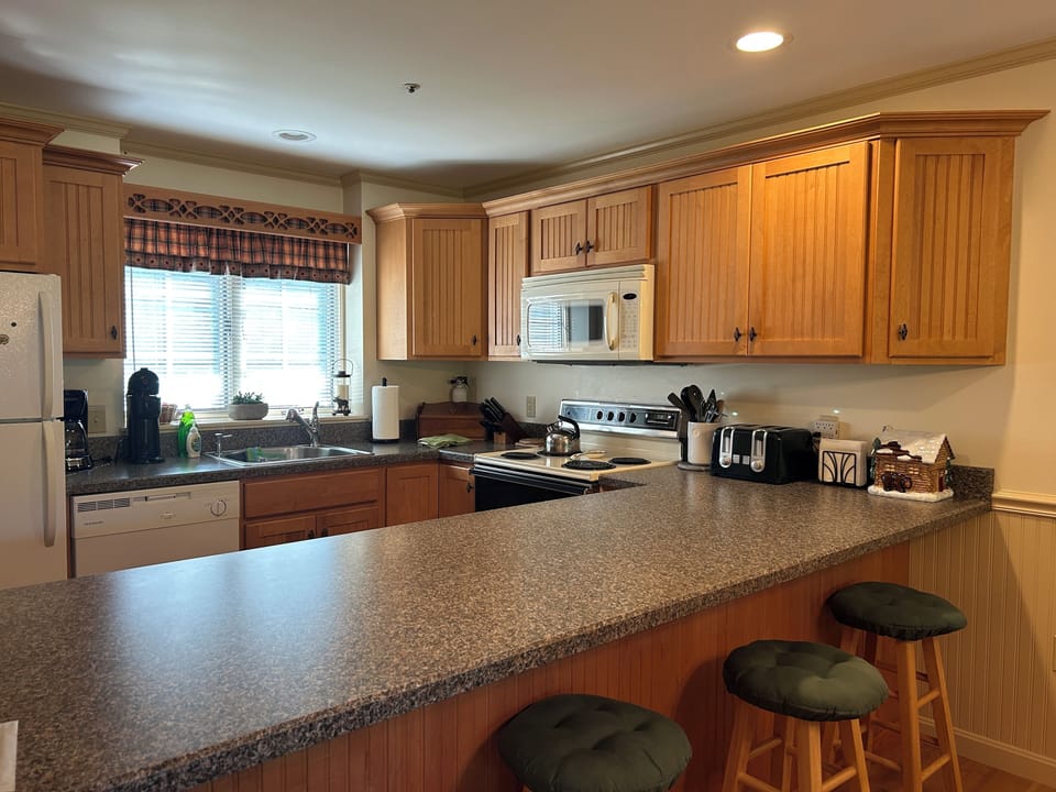 kitchen area- with 4 bar stools for additional seating  next to table.