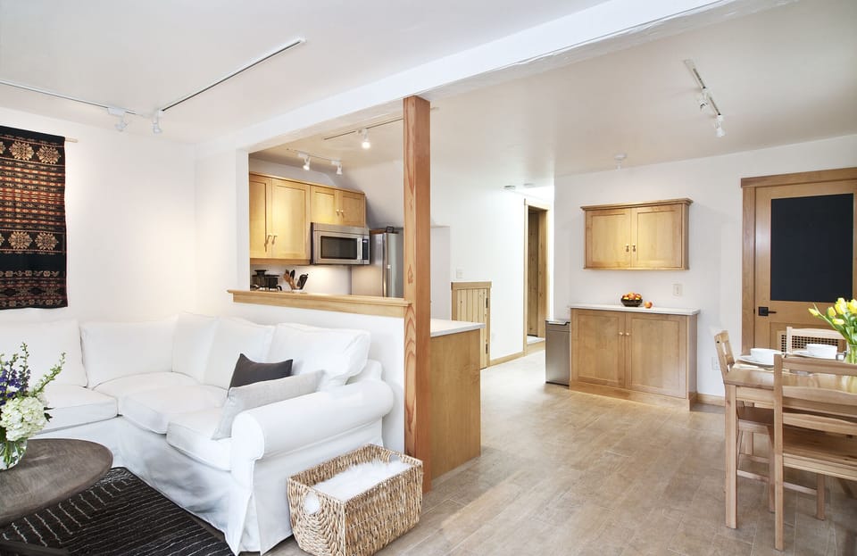 Spacious + light-filled great room with open kitchen, dining + living room areas