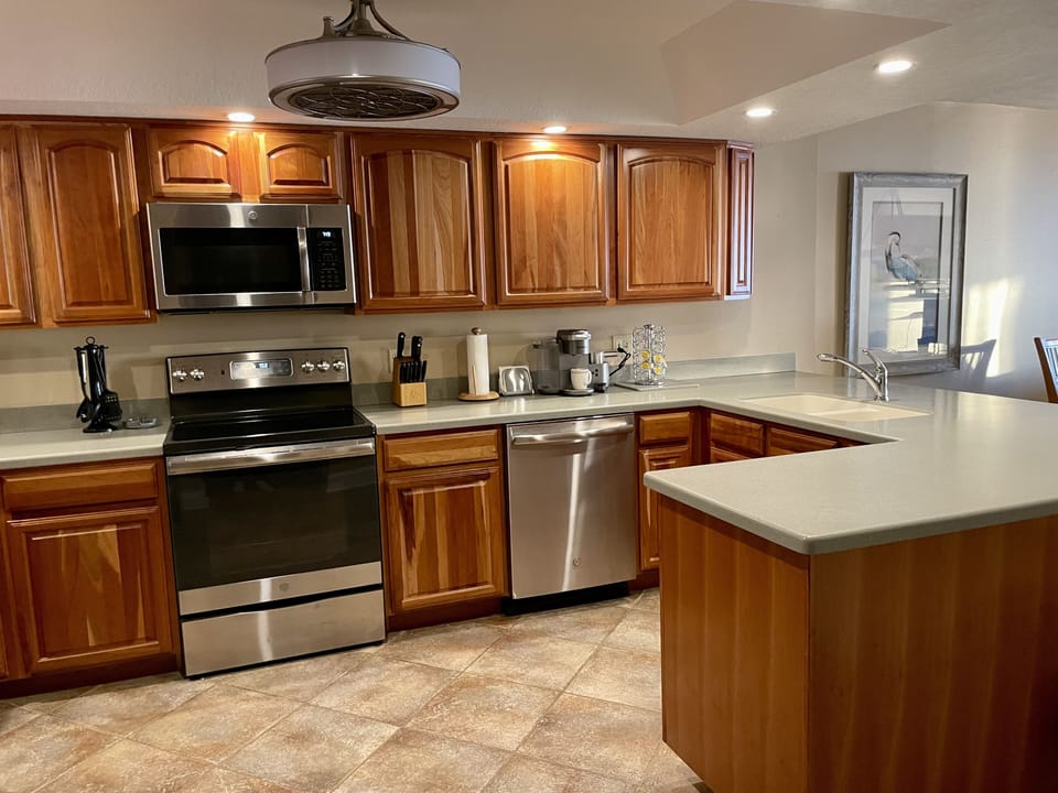 Kitchen with corian countertops and stainless steel appliances.
