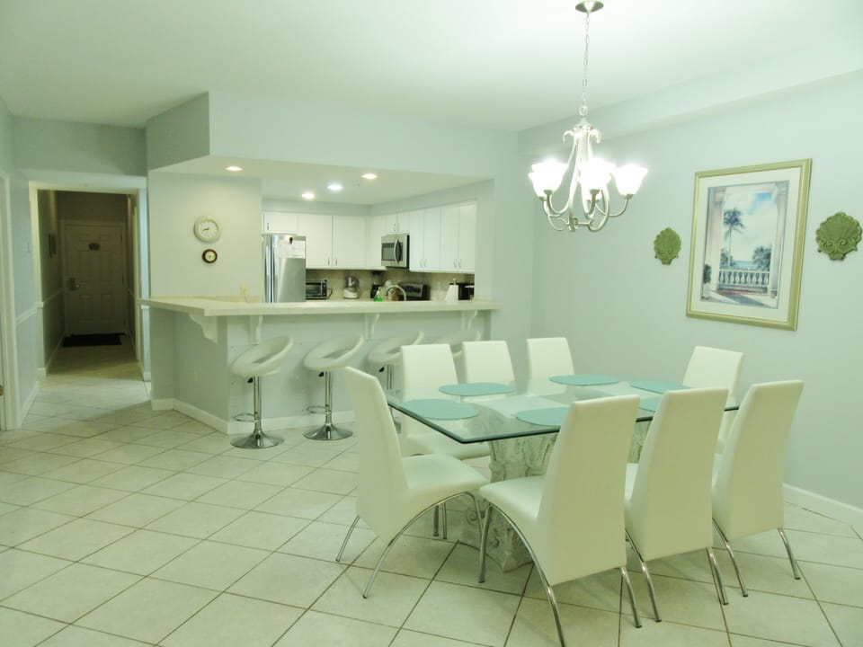 White leather dining chairs and bar stools provide ample seating for families