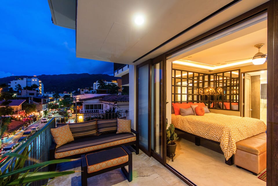 Terrace view into master bedroom at dusk, city lights beginning to show