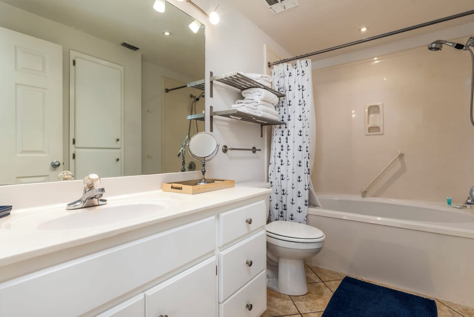 Your nautical-themed bathroom features fresh towels, a soaking tub, and charming anchor details for a relaxing coastal retreat.