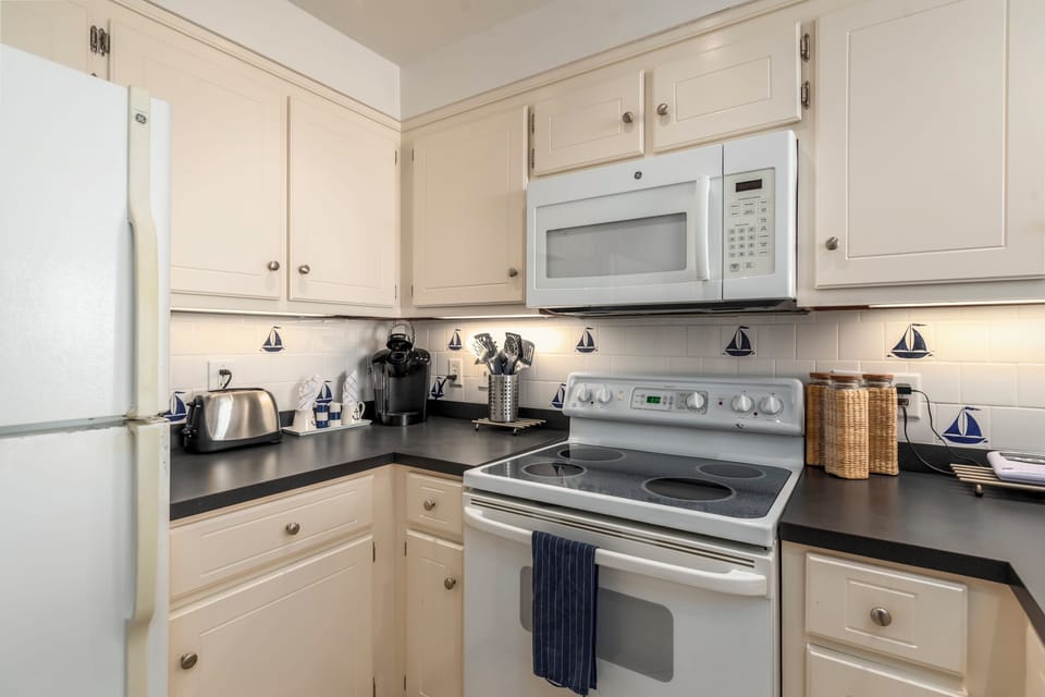 Your bright, fully-equipped kitchen features white cabinetry, sleek appliances, and charming nautical touches—perfect for preparing coastal meals together.