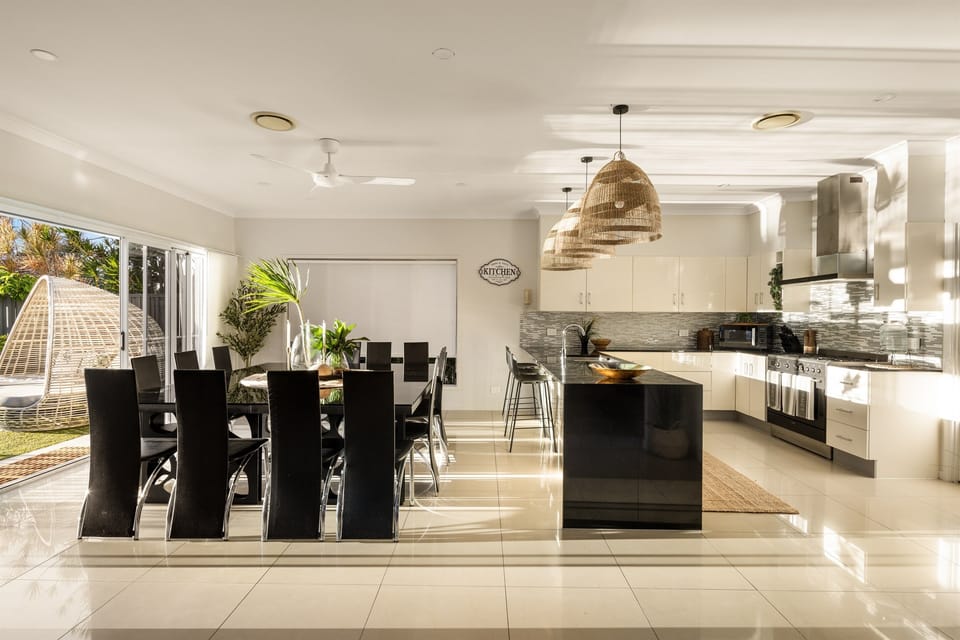Expansive dining area with seating for large group meals, flowing into the fully equipped kitchen and open-plan living space.