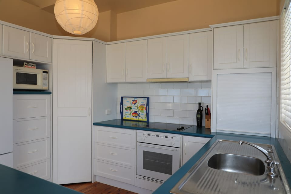 Kitchen showing fridge, microwave, corner pantry, cooktop, rangehood & oven