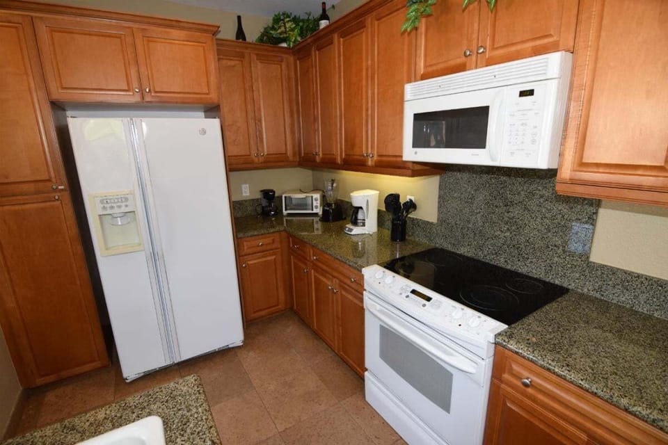 This well-equipped kitchen includes a refrigerator, oven, microwave, coffee maker, and essential cookware — making meal prep easy after a day at the pool.