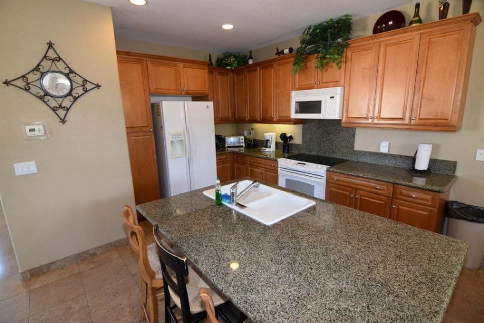 The kitchen island features bar stool seating for two — a convenient spot for quick breakfasts or morning coffee before heading to the pool.