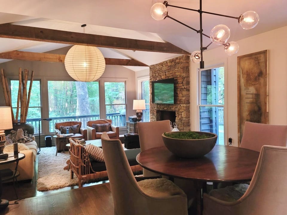 RH tea table and den w stacked stone fireplace and view of Green-belt/Mtn Stream
