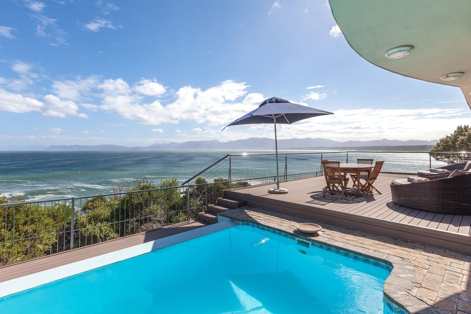 salt-water, rim flow pool with solar cover and deck views of ocean and moun